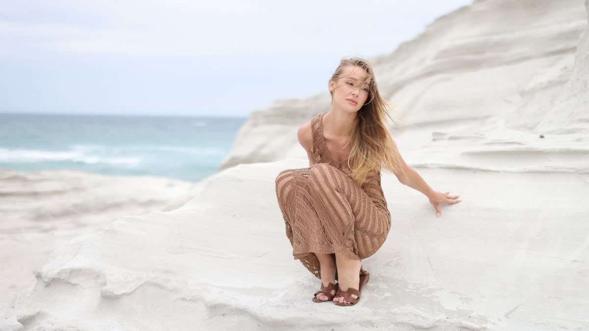 Model in a Greek Summer knit dress on white rocks by the sea